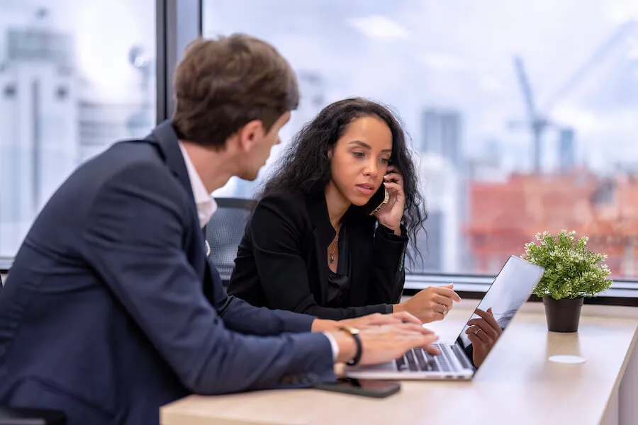 woman talking on phone while man looks at laptop