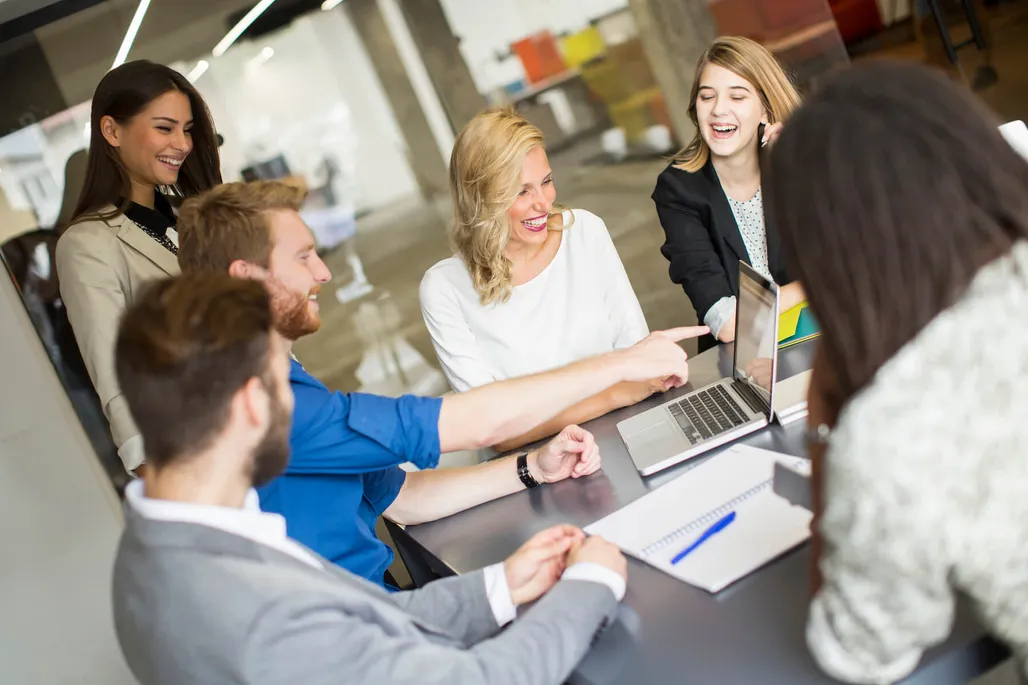 business team collaborating while looking at laptop computer